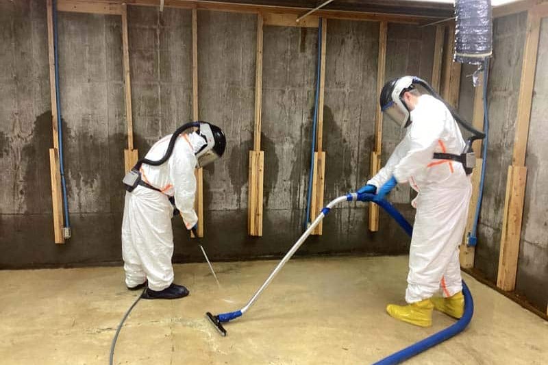 Technician in protective gear cleaning a contaminated floor